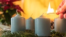 Kerzen müssen angezündet werden, doch was ist nachhaltiger: Streichhölzer oder ein Feuerzeug? Im Bild: Mann zündet eine Kerze am Adventskranz an. | Bild: colourbox.com