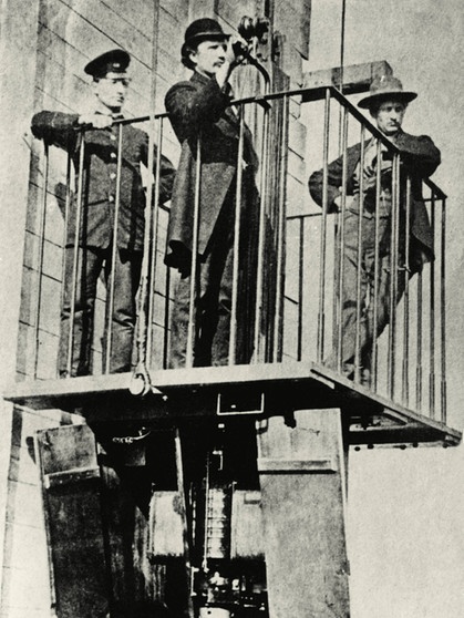 Erster elektrischer Fahrstuhl, ausgestellt auf der Mannheimer Industrieausstellung 1880, gebaut von Werner Siemens. Der Elektromotor befindet sich unter der Kabine. | Bild: picture-alliance/dpa/akg-images
