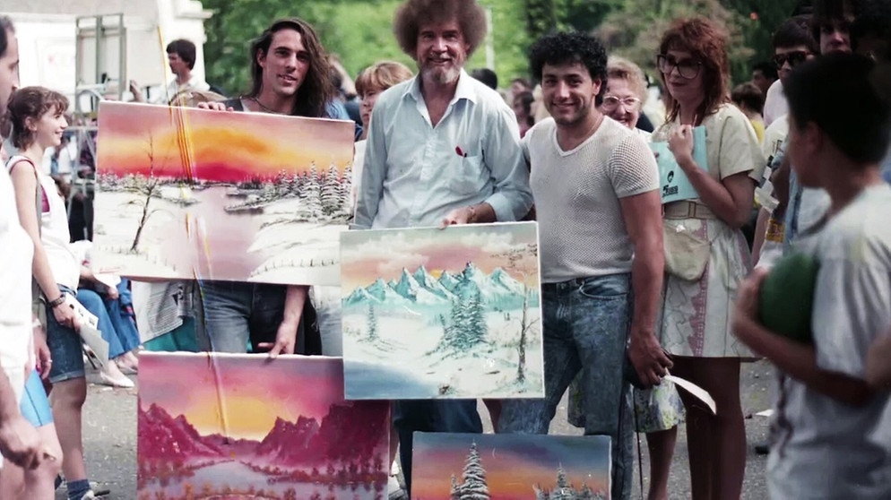 Bob Ross traf seine Fans bei einem Event in den 1980er-Jahren im New Yorker Central Park. Viele seiner Anhänger zeigten ihm damals ihre mit Ölfarbe gemalten Bilder.  | Bild: picture alliance / Everett Collection | ©Netflix/Courtesy Everett Collection