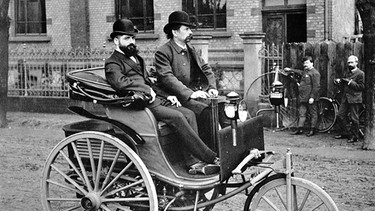 Carl Benz am Steuer eines Patent-Motorwagens im Jahr 1887. Carl Benz erntete zunächst Spott für den "Motorwagen Nummer 1". Doch das Fahrzeug mit drei Rädern wurde zum Meilenstein. Auch Bertha Benz schrieb Geschichte. | Bild: Daimler