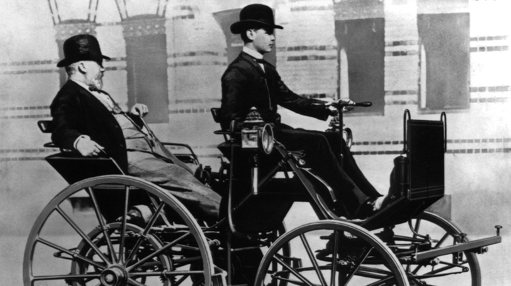 Gottlieb Daimler wird von seinem Sohn Adolf Daimler in einer "Motorkutsche" chauffiert | Bild: picture-alliance/dpa