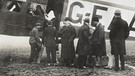 Passagiere mit ihrem Gepäck vor einer Handley Page Transport O7400 im Jahr 1919, kurz nach Ende des Ersten Weltkriegs, die von London nach Paris flog. Seit 100 Jahren servieren Airlines ihren Passagieren Essen im Flugzeug. | Bild: picture alliance/Mary Evans Picture Library