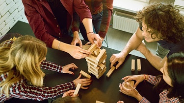 Freunde spielen gemeinsam ein Turmspiel. Viele Brettspiele wie Schach, "Mensch ärgere dich nicht" und Mühle sind mehrere Jahrhunderte alt. | Bild: colourbox.com