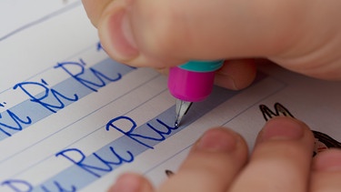 Was ist die besser Handschrift: Schreibschrift oder Druckbuchstaben? Im Bild: Kind übt schreiben (Nahaufnahme). | Bild: picture alliance / Zoonar | DesignIt