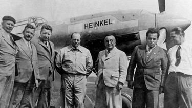 Ernst Heinkel (3. von rechts) vor der He 100. Der Jungfernflug des ersten Düsenflugzeugs fand unter Geheimhaltung statt. Am 27. August 1939 hob die He 178 ab. Am Zweiten Weltkrieg waren die Düsenflieger nicht beteiligt, aber andere Flugzeuge aus den Heinkel-Werken. | Bild: picture-alliance/dpa