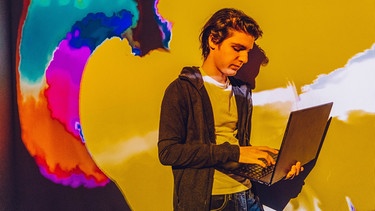 Ein Junge mit einem PC vor einem bunten Hintergrund | Bild: colourbox.com