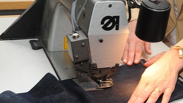 Frau näht an Nähmaschine eine Hose | Bild: picture-alliance/dpa