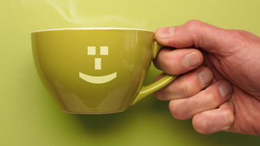 Eine Hand hält eine Tasse mit Smiley-Aufdruck von rechts ins Bild | Bild: picture-alliance/Zoonar|Andreas Berheide