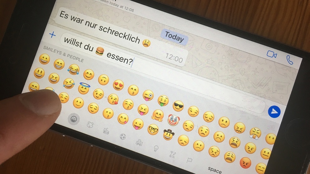 Jemand tippt auf dem Smartphone eine Whatsapp-Nachricht mit Emojis | Bild: picture-alliance/dpa/Christiane Oelrich