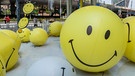 Große Bälle mit Smiley-Gesichtern liegen vor einem Kaufhaus | Bild: picture-alliance/Wang Gang/Costfoto