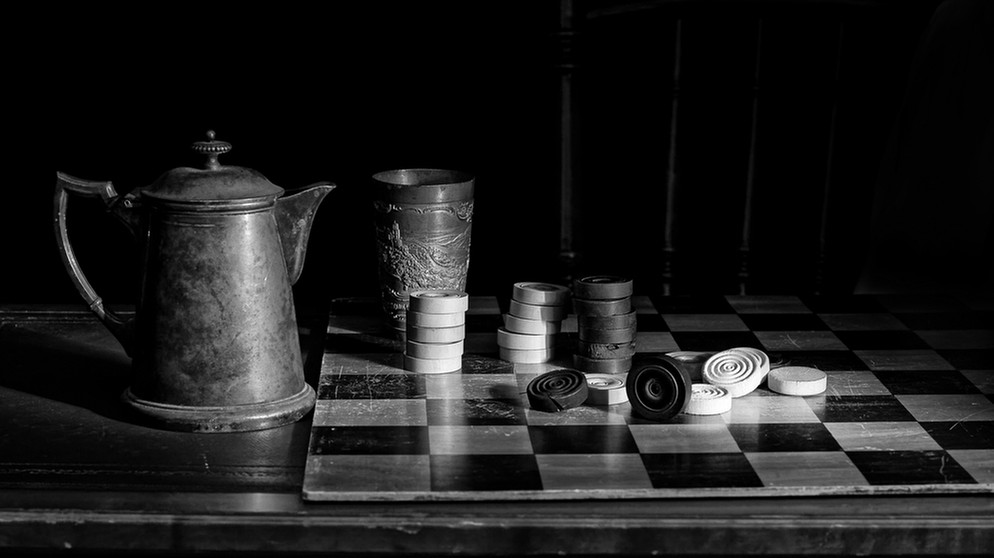 Neben einem alten Mühle-Spiel stehen zwei Krüge. Klassische Gesellschaftsspiele und Brettspiele wie Mühle, Schach und "Mensch ärgere dich nicht" wurden bereits vor Jahrhunderten gespielt. | Bild: picture-alliance/dpa