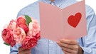EIn Mann hält einen Blumenstrauß und eine Karte in der Hand - zum Valentinstag | Bild: picture alliance / Zoonar | lev dolgachov