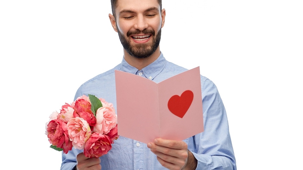 EIn Mann hält einen Blumenstrauß und eine Karte in der Hand - zum Valentinstag | Bild: picture alliance / Zoonar | lev dolgachov