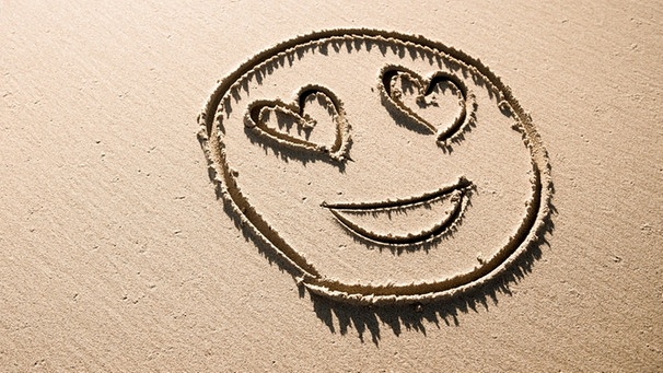 Ein in den Sand gezeichnetes Emoji mit Herzchenaugen | Bild: colourbox.com