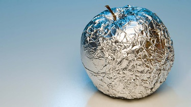 Ein Apfel ist in Alufolie eingewickelt. Aluminium wird durch Lebensmittel und Kosmetik vom Körper aufgenommen. | Bild: colourbox.com