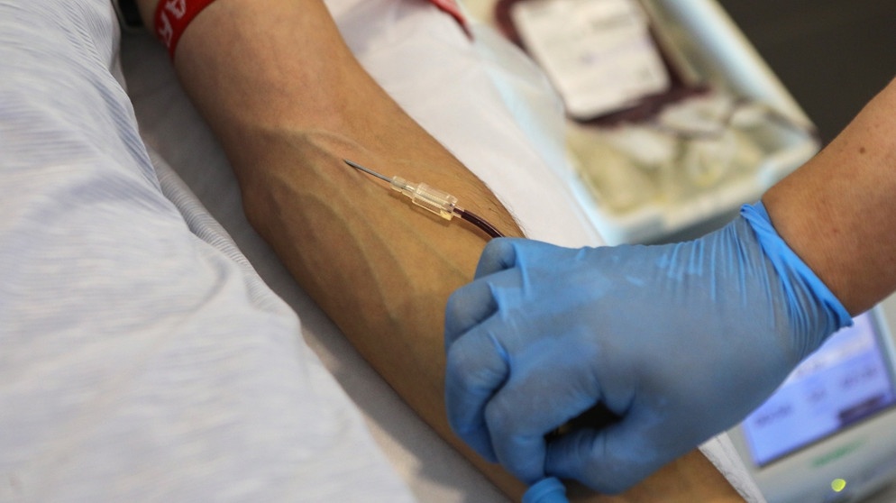 Ein Mitarbeiter eines Gesundheitszentrums führt einem Blutspender einen Katheter über eine Vene ein. | Bild: picture-alliance/dpa/Photoshot/Yuliia Ovsiannikova /Avalon