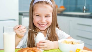 Mädchen isst gekochtes Ei zum Frühstück. Zu Ostern legen wir hartgekochte Ostereier ins Osternest. | Bild: colourbox.com