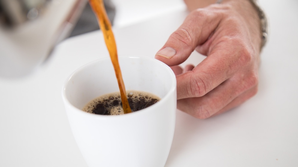 In vielen Lokalen wird zum Kaffee ein Glas Wasser serviert. Macht das Sinn? Auf diesem Bild gießt sich ein Mann eine Tasse Kaffee ein.  | Bild: picture alliance/dpa Themendienst