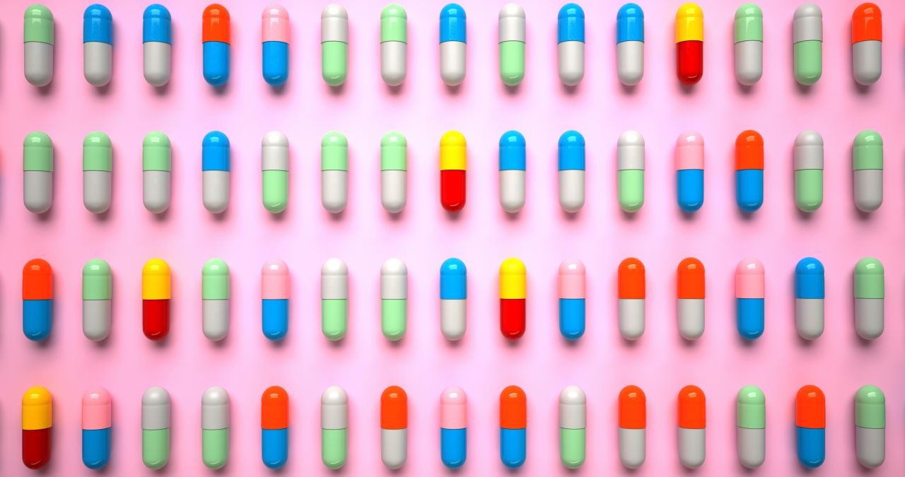 Gerade angeordnet einzelne Tabletten in unterschiedlichen Farben auf rosa Untergrund in vier Reihen. Geht es nach der Werbung, benötigen wir alle zusätzliche Vitamine und Mineralstoffe für unsere Gesundheit. Aber stimmt das? | Bild: picture alliance / Zoonar | Alexander Limbach