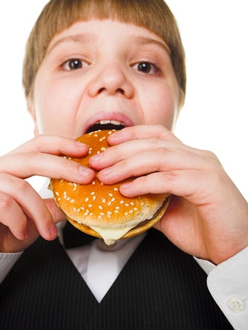 Junge beißt in Hamburger, Fastfood kann zu Lebensmittelunverträglichkeiten führen. | Bild: colourbox.com