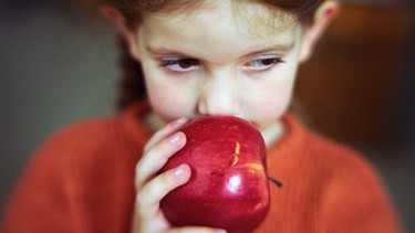 Mädchen hält Apfel an den Mund, ein Obst, das eine Lebensmittelallergie hervorrufen kann. | Bild: colourbox.com