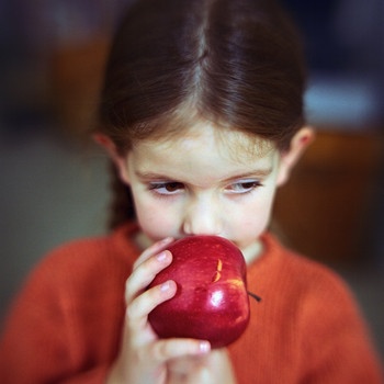 Mädchen hält Apfel an den Mund, ein Obst, das eine Lebensmittelallergie hervorrufen kann. | Bild: colourbox.com