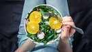 Alles Vegan: Junge Frau isst aus einem Teller mit Spinat, Radieschen und Orangenscheiben. | Bild:  picture alliance/Zoonar/Olga Sergeeva