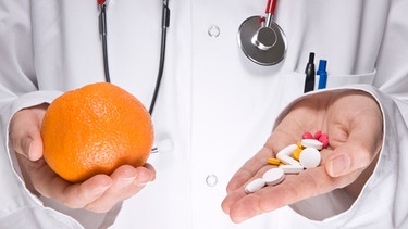 Ein Arzt hält eine Orange in der einen und Vitamintabletten in der anderen Hand. Was ist gesünder? | Bild: Bing Maps