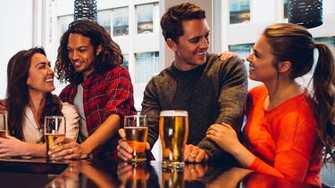 Eine Gruppe von Freunde genießen ein Bier in der Bar.  | Bild: picture alliance / PantherMedia | Graham Oliver