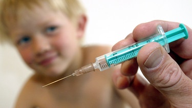 Die Empfehlungen der Ständigen Impfkommission sehen viele Impfungen im Kindesalter vor. Im Bild: Kind im Hintergrund, Spritze im Vordergrund  | Bild: picture-alliance/dpa