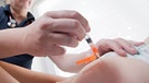 Ein Kinderarzt impft ein einjähriges Kind in den Oberschenkel mit dem Impfstoff Priorix  | Bild: picture alliance/dpa, Julian Stratenschulte