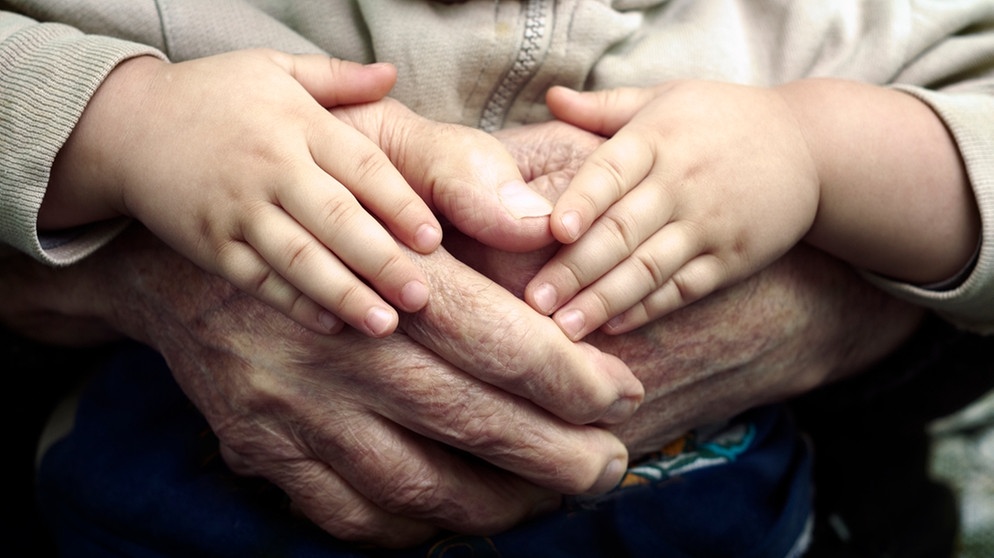 Ein Kind hat seine Hände auf die Hände eines alten Menschen gelegt. Können wir Menschen bald schon viel länger und gesünder leben? Wir erklären euch aussichtsreiche wissenschaftlichen Entdeckungen der Alternsforschung für ein gesundes Altern und ein längeres Leben. | Bild: colourbox.com