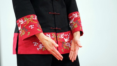 Bei Rückenschmerzen ist Qigong auch eine alternative Behandlungsmethode (im Bild: Frau mit traditioneller chinesischer Kleidung hält Hände vor Hüften) | Bild: colourbox.com