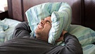 Verzweifelter Mann hält sich ein Kopfkissen an die Ohren | Bild: colourbox.com