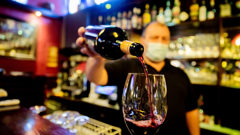 Ein Kneipenwirt schenkt in einer Gaststätte einen Rotwein ein. | Bild: picture-alliance/dpa/ Christoph Soeder