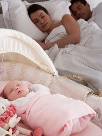 Schlafende Familie: Schlafendes Paar im Bett im Hintergrund, schlafendes Baby in Krippe im Vordergrund.  | Bild: colourbox.com