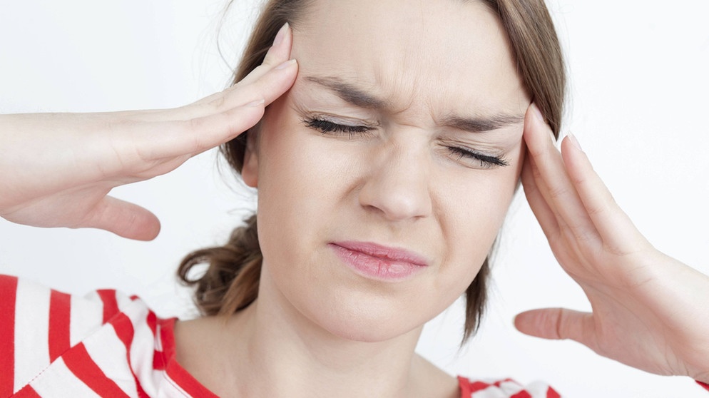 Wetterfühlige Frau hat Migräne Kopfschmerz. Sie hält sich die Hände an die Schläfen und kneift die Augen fest zu. | Bild: picture-alliance/dpa