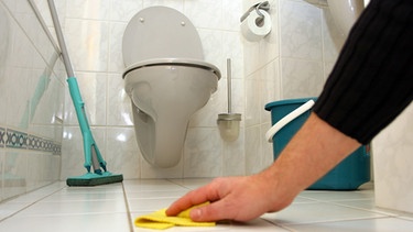 Hand mit Lappen wischt Boden von Toilette | Bild: picture-alliance/dpa
