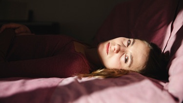 Eine Frau liegt erschöpft im Bett. Die Krankheit Myalgische Enzephalomyalgie oder ME/CFS ist auch bekannt als Chronisches Erschöpfungssyndrom. Sie fühlt sich an wie eine jahrelang andauernde Grippe. | Bild: picture alliance / Westend61 | Michela Ravasio