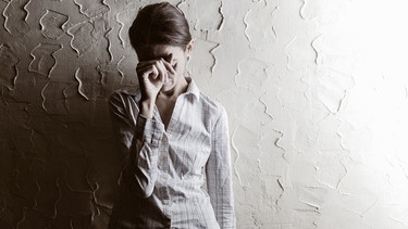 Eine Frau vor einer grauen Wand fasst sich an die Stirn. Freudlosigkeit, Antriebsmangel, Traurigkeit, Erschöpfung - das können Symptome einer Depression sein. Obwohl viele an der psychischen Erkrankung leiden, wird nur wenig darüber gesprochen. Hier findet ihr Infos und Anlaufstellen. | Bild: colourbox.com