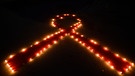 Eine HIV-Schleife aus Kerzen. | Bild: picture-alliance/dpa
