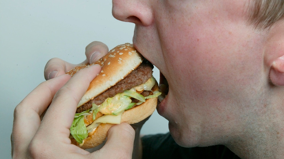 Ein Mann beißt in einen Burger  | Bild: picture-alliance/dpa/Ulrich Baumgartner