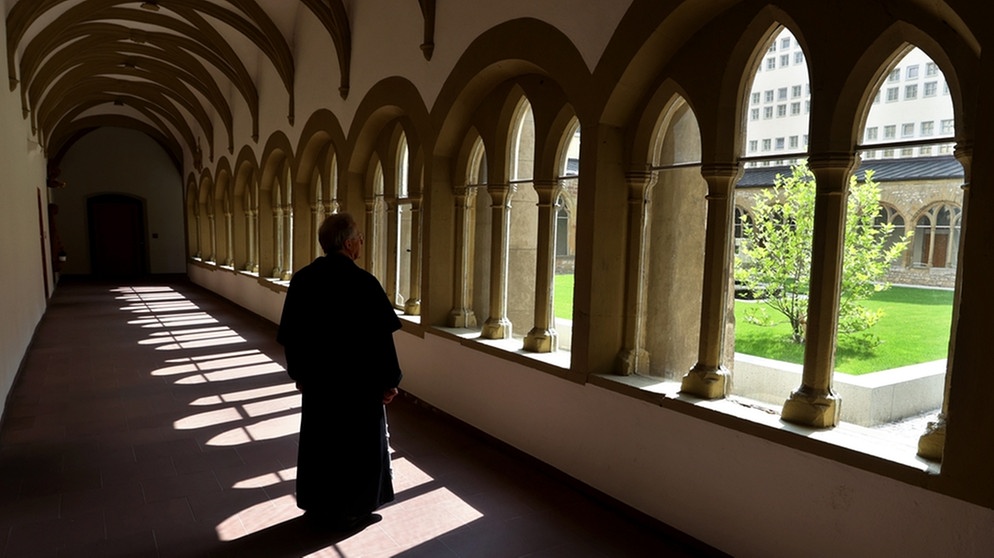 Ein Mönch steht im Kreuzgang des Würzburger Franziskanerklosters. | Bild: picture-alliance/Karl-Josef Hildenbrand