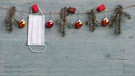 Adventskette mit Zweigen, Christbaumkugeln und einer aufgehängten Mund-Nasen-Maske. | Bild: Colourbox.com