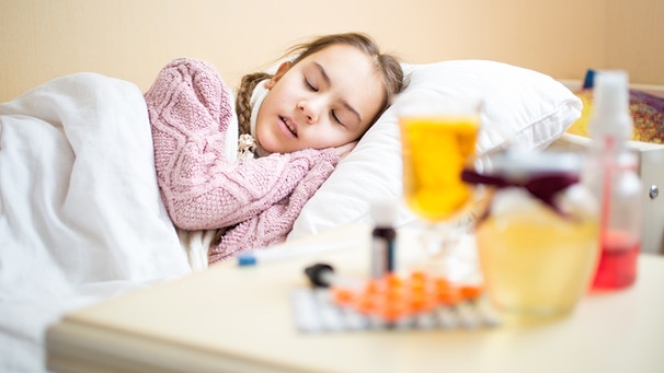 Kind liegt krank im Bett. Im Vordergrund verschwommen Medikamente | Bild: colourbox.com