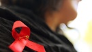 Epidemien vor Corona: Frau mit roter Aids-Schleife | Bild: picture-alliance/dpa