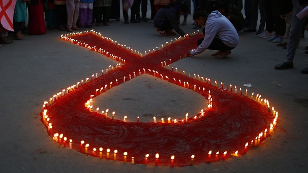 ARCHIV - 30.11.2018, Nepal, Kathmandu: Aktivisten stellen auf einer Veranstaltung im Vorfeld des Welt-Aids-Tags Kerzen auf, die eine rote Schleife formen - ein weltweit anerkanntes Symbol für die Solidarität mit HIV-Infizierten. (Zu dpa «UNAIDS: Corona-Pandemie ist Rückschlag für Kampf gegen HI-Virus») Foto: Skanda Gautam/ZUMA Wire/dpa +++ dpa-Bildfunk +++ | Bild: dpa-Bildfunk/Skanda Gautam