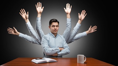Ein Mann sitzt vor dem Schreibtisch und hat mehrere Arme. Multitasking ist nicht immer zielführend und kann sogar kontraproduktiv sein.  | Bild: colourbox.com