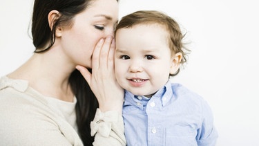Mutter flüstert ihrem kleinen Sohn ins Ohr. | Bild: picture-alliance/dpa / Bildagentur-online
