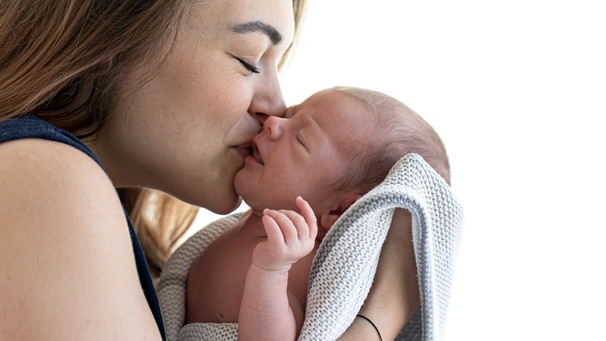 Eine Mutter küsst ihr neugeborenes Baby. Reproduktionsmedizin kann bei unerfülltem Kinderwunsch helfen. Mehr als zehn Millionen Kinder wurden bisher durch Künstliche Befruchtung geboren. | Bild: colourbox.com
